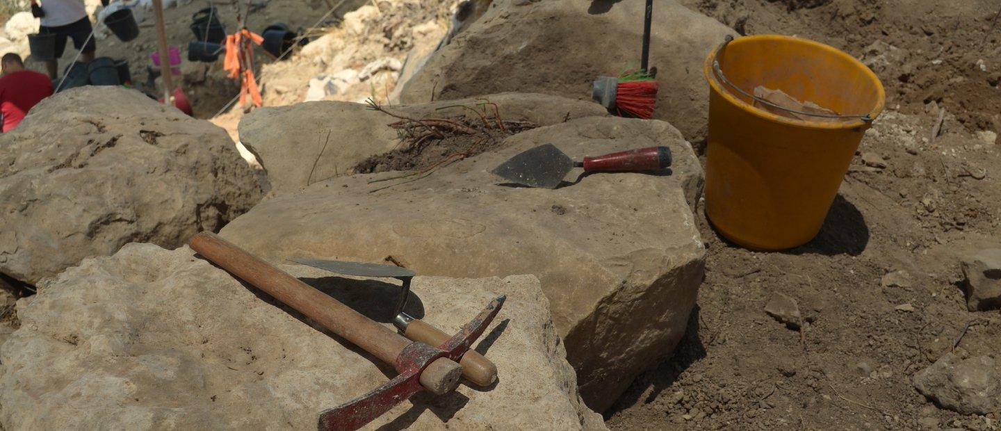 Tools sitting on rocks at an archaeological dig site.