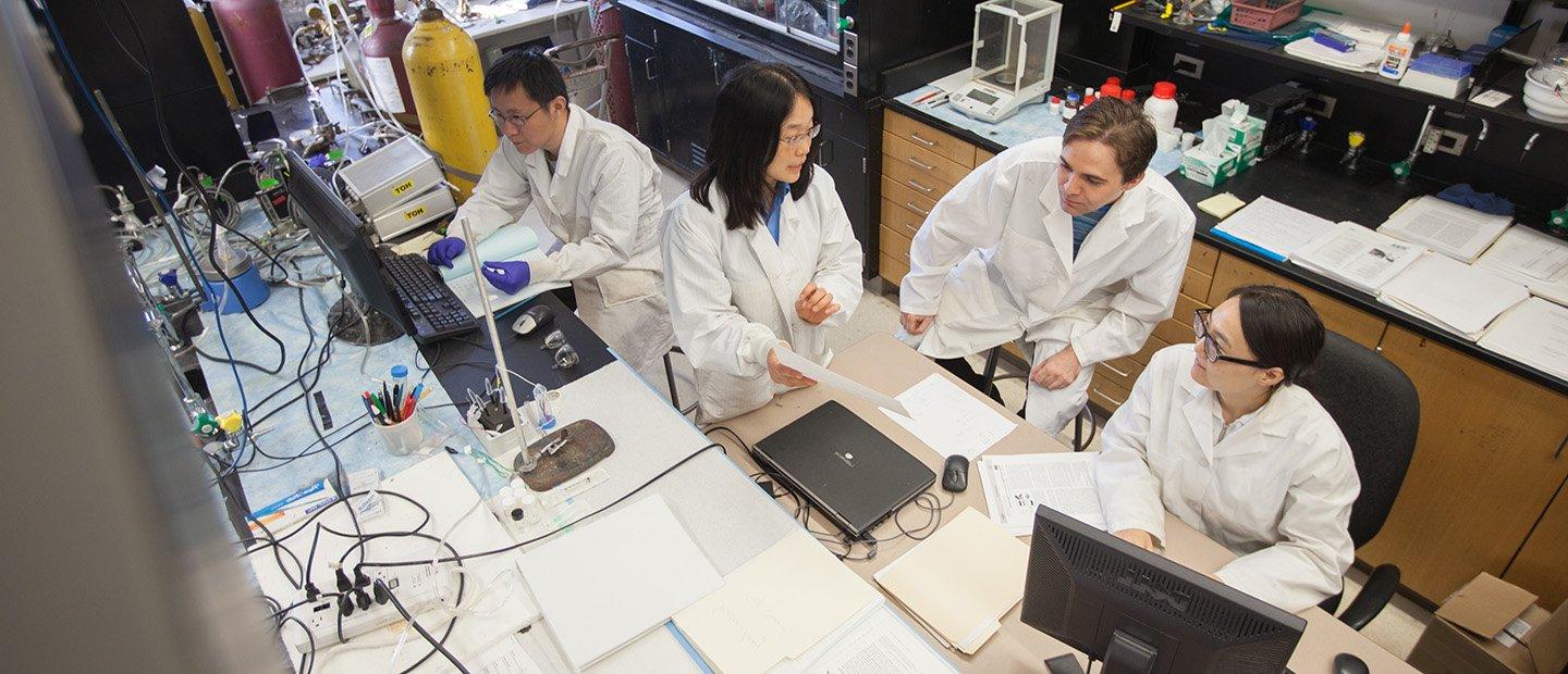 People in white lab coats working in a research lab.
